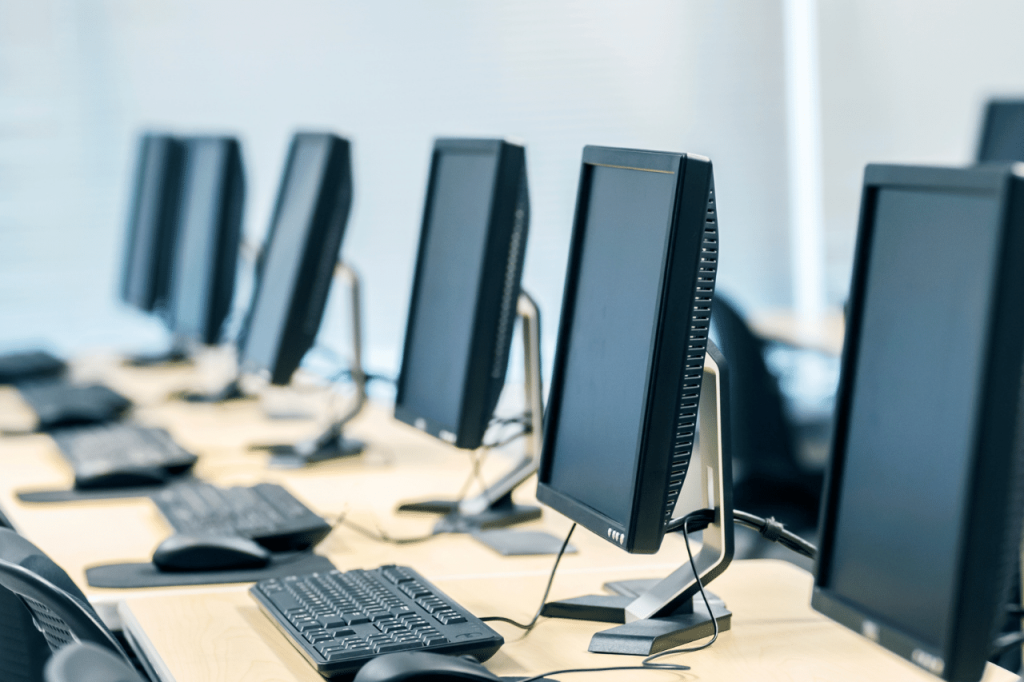 office table with computer screens, mouses and keyboards